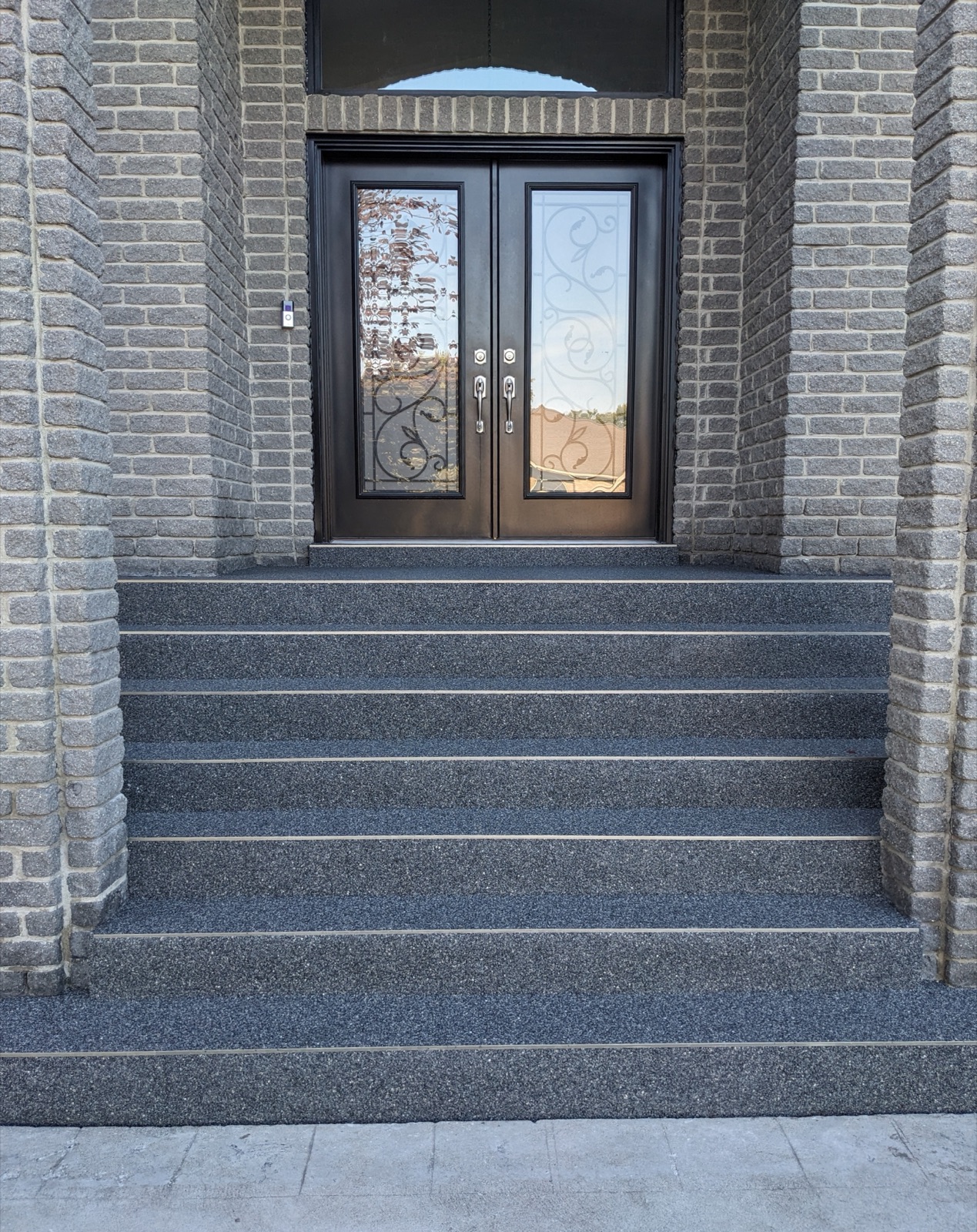 Grand dark grey resin steps at a double-door entry — after