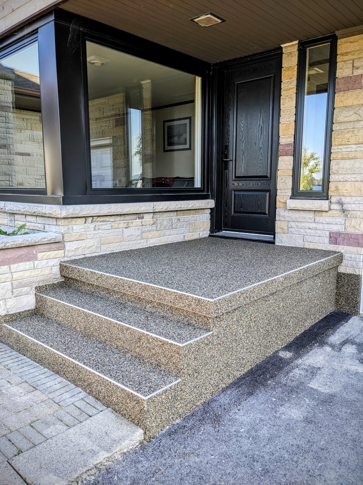 Grey resin patio against a stone-clad facade — after