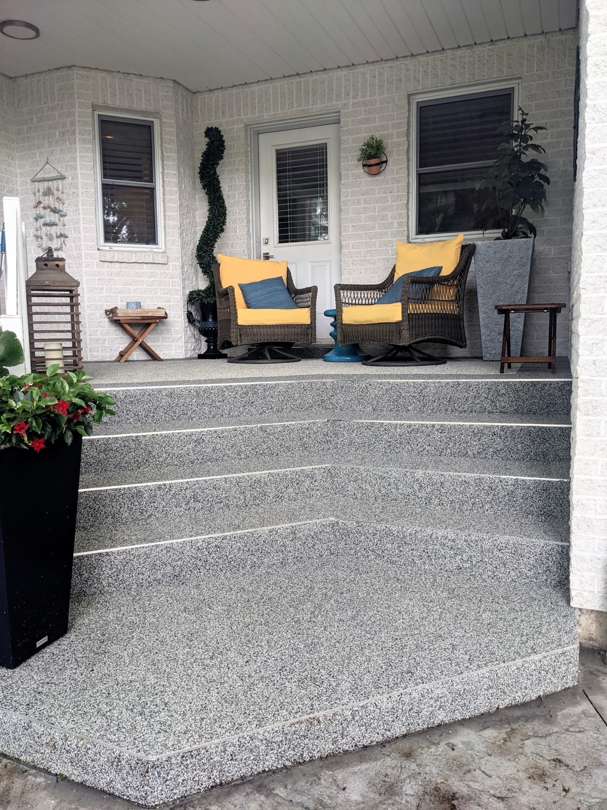Grey resin porch with yellow accent pillows — after