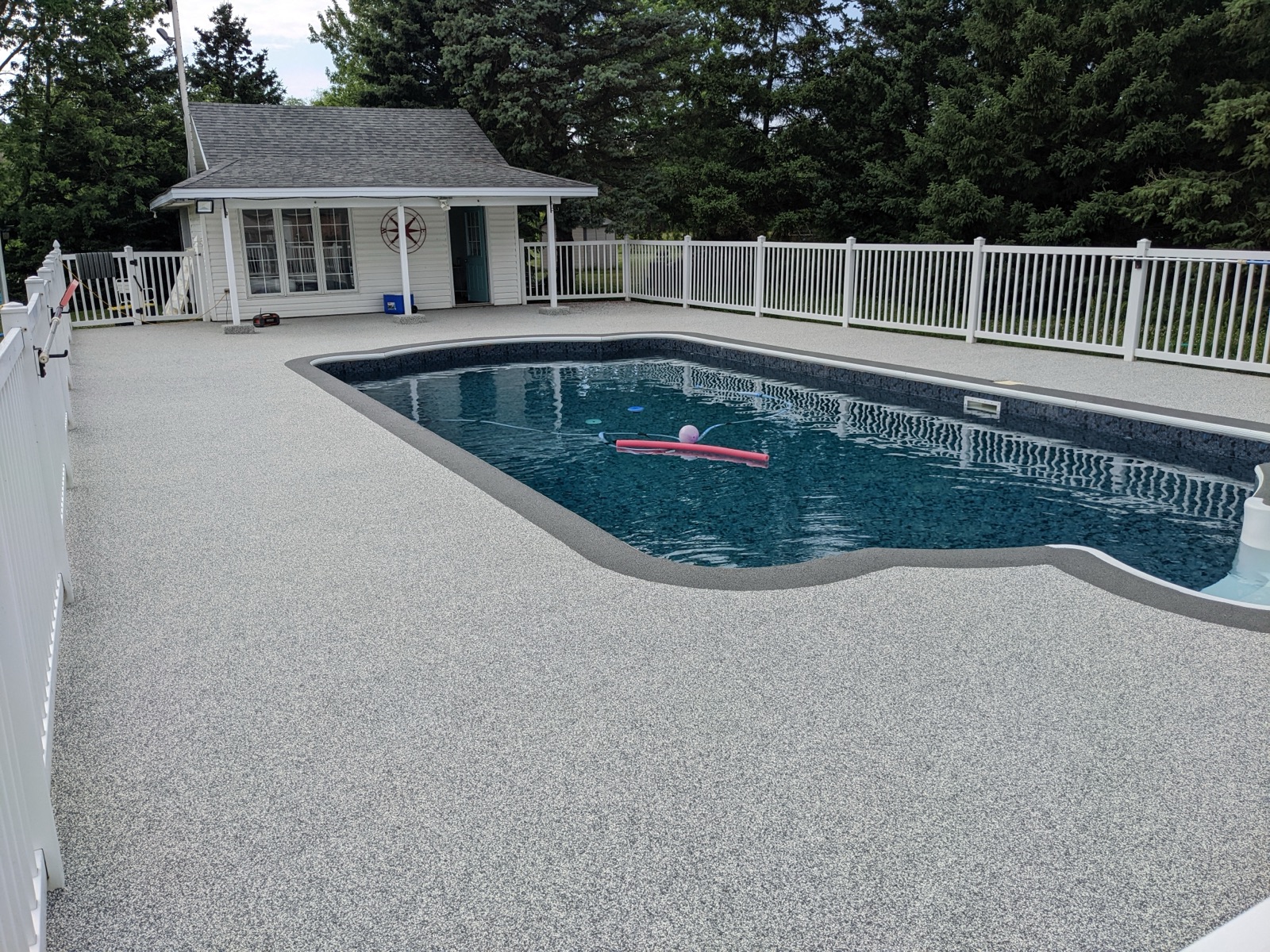 Grey resin pool deck with slat fence — after