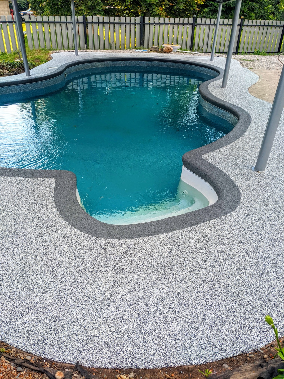 Grey resin pool deck with slat fence alternate — after