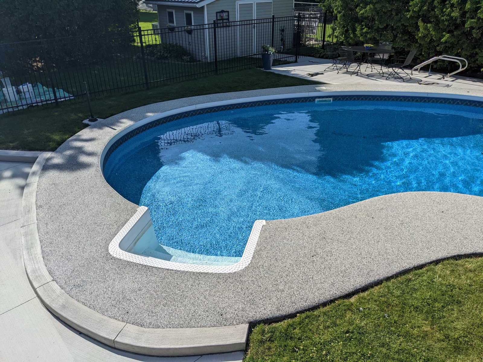 Grey resin pool deck with white fence — after