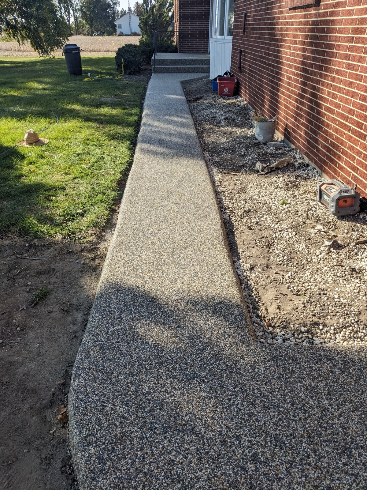 Grey permeable side path alongside a brick house — after